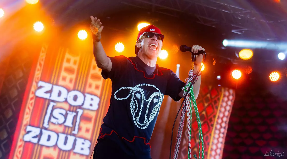 Roman Iagupov, cu ochelari și cu o șapcă roșie pe cap, cântă pe scenă la microfon