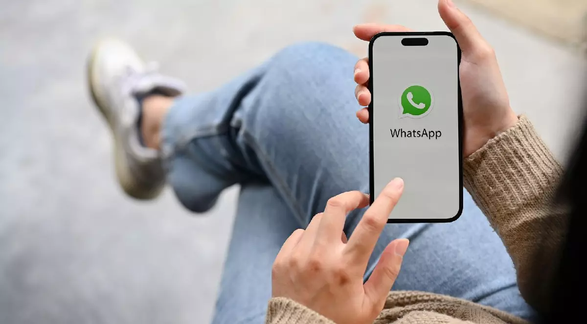 O mână de femeie ținând un smartphone cu logo-ul aplicației WhatsApp pe ecran.