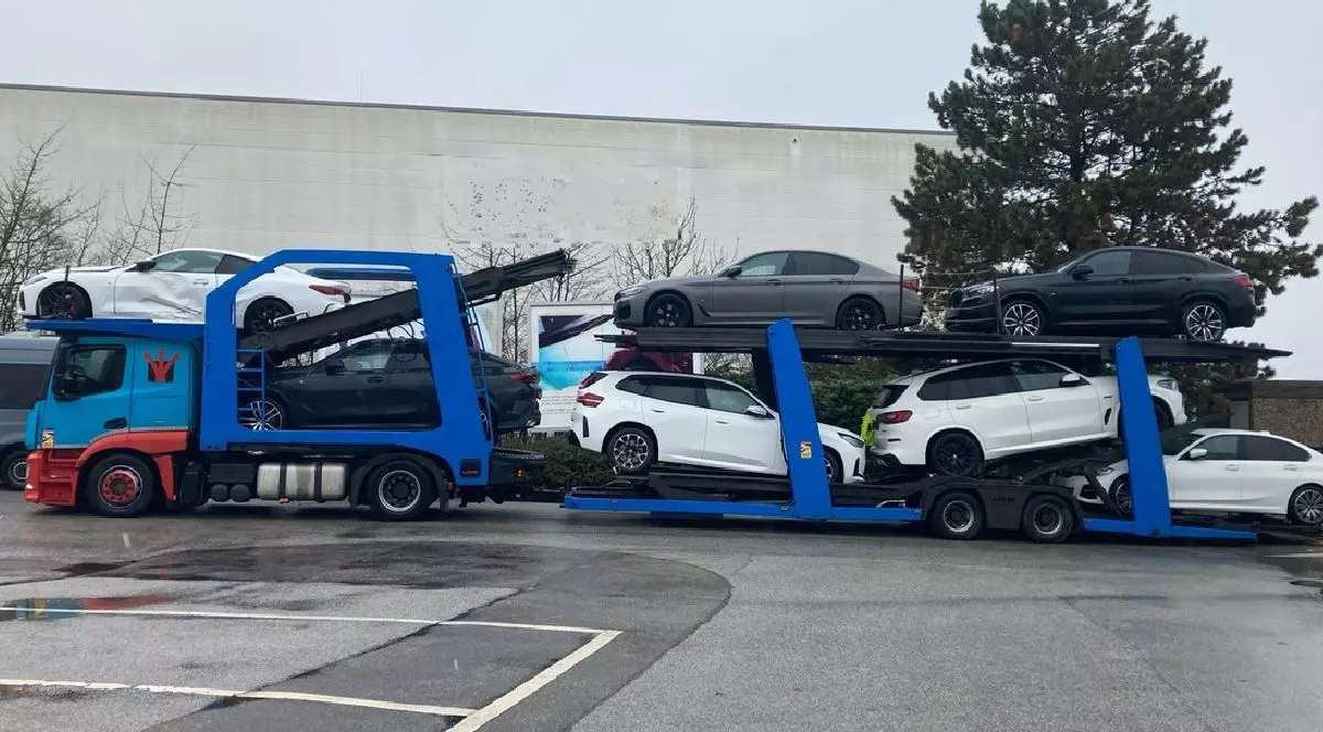 Imaginea arată un camion albastru care transporta mai multe mașini