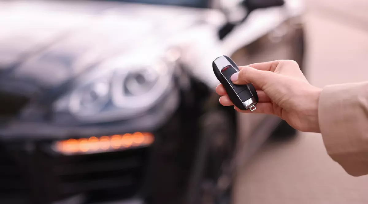 O femeie ține cheia mașinii lângă vehiculul său în aer liber