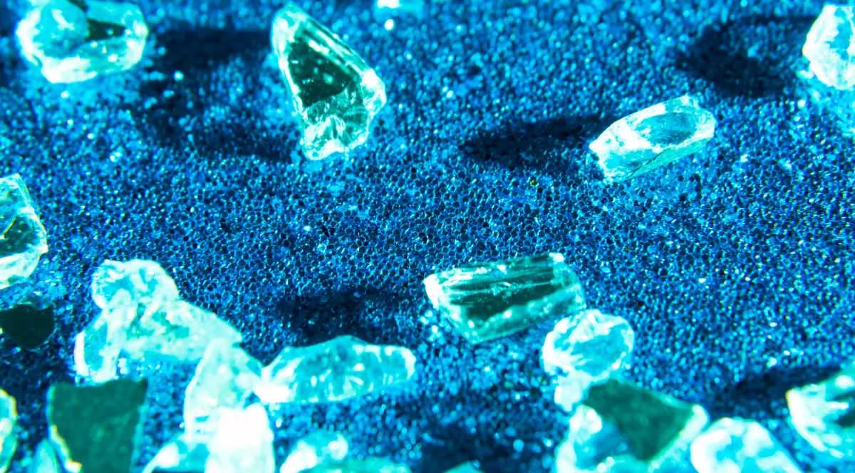 Mai multe diamante verzi pe un fundal albastru strălucitor. Pietrele sunt în stare pură