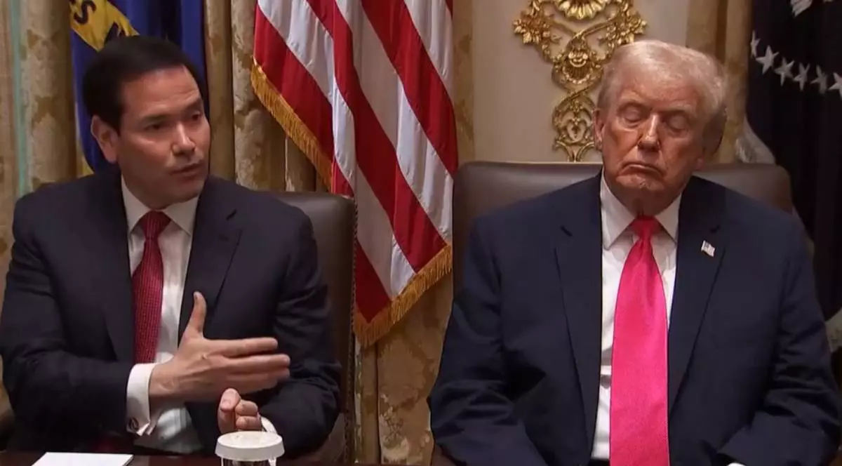 Marco Rubio in stanga, in sacou negru si cravata rosie,, aratand cu mana streapta spre presedintele Donald Trump, in dreapta imaginii, in sacou negru si cravata rosie, care sta cu ochii inchisi, 2 decembrie 2025