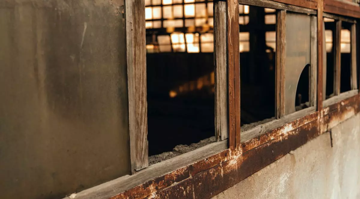 Un garaj vechi, fotografiat din exterior, cu trei geamuri sparte și unul încă întreg