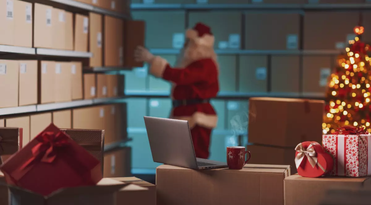 Un moș Crăciun care așează coletele în cutie de carton