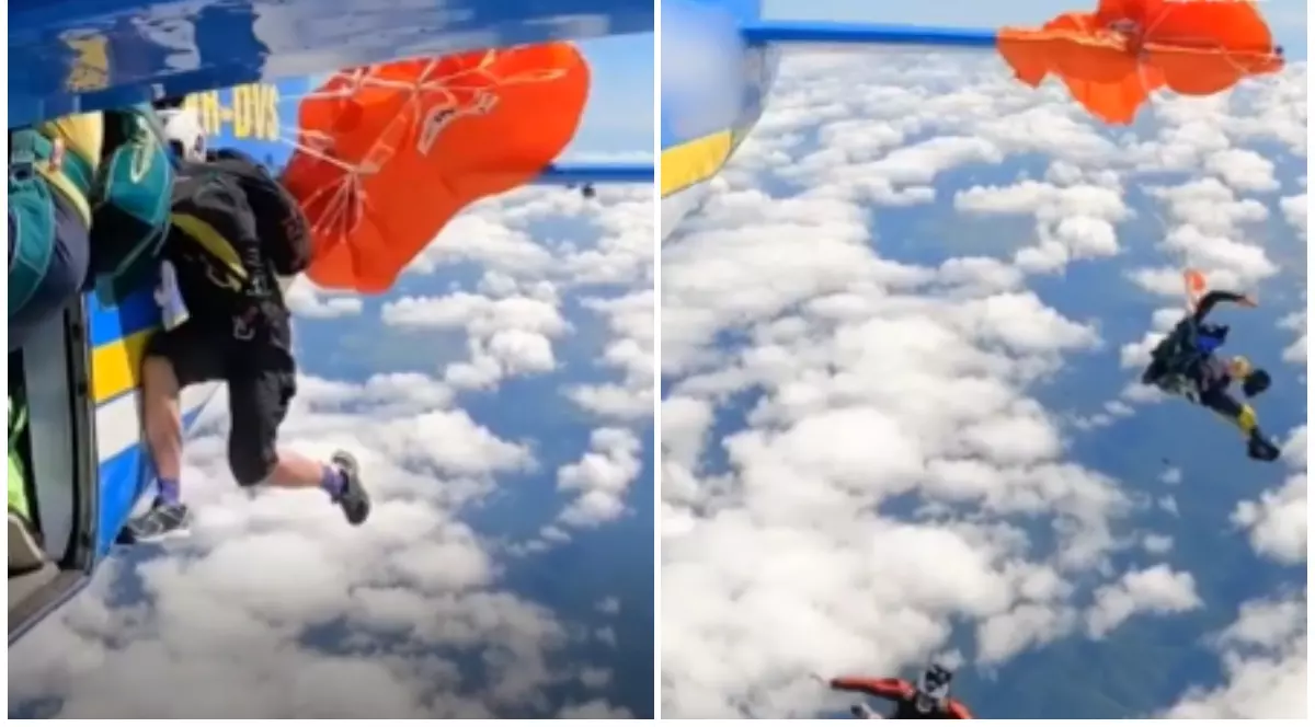 Un bărbat care a rămas agățat cu parașuta portocalie de avion, în aer.