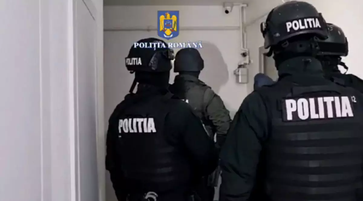 Mai mulți polițiști la ușa unui apartament în vederea unei percheziții