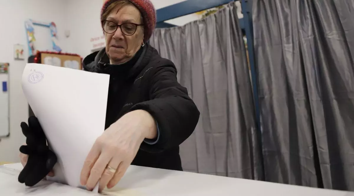 o femeie care introduce un buletin de vot în urnă