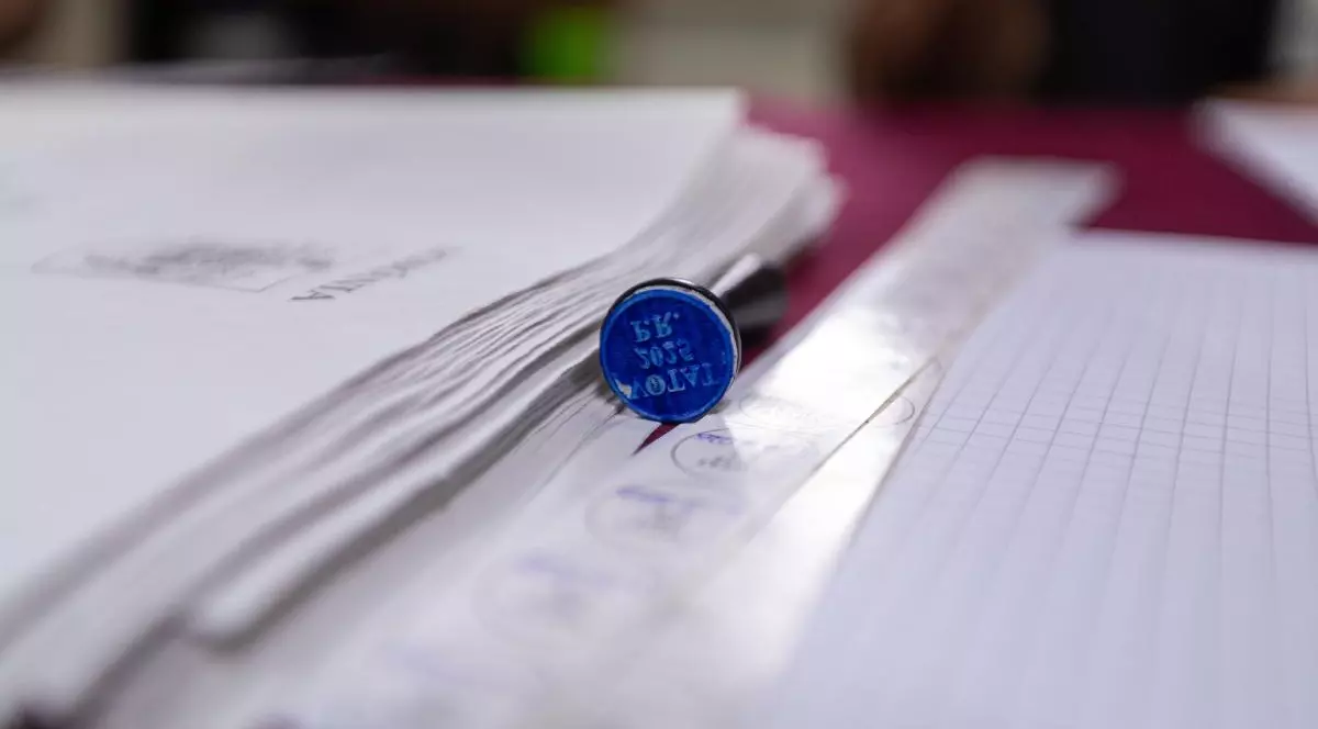 O ștampilă de vot 2025 și mai multe buletine de vot, pe o masă.