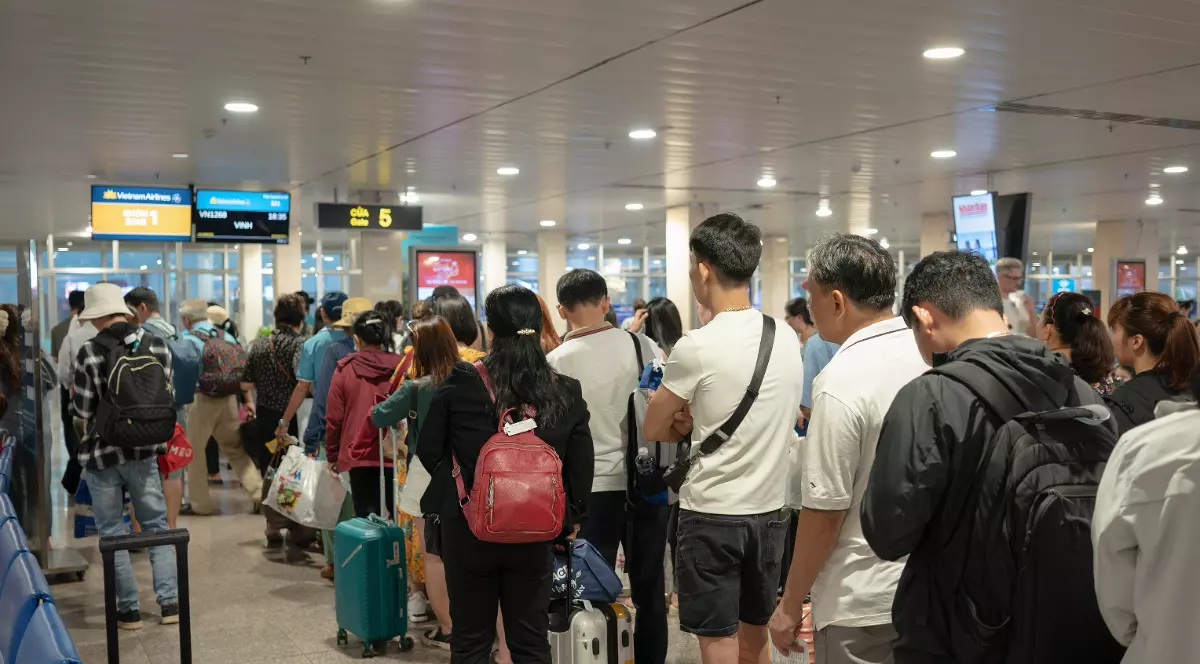 Imaginea surprinde o coadă lungă de pasageri adunați la poarta de îmbarcare dintr-un aeroport, mulți dintre ei stând în picioare cu bagajele de mână, deși îmbarcarea pare să nu fi început încă. Scena ilustrează nerăbdarea și aglomerația tipică acestui moment, cunoscută drept fenomenul pasagerilor care se ridică prea devreme la poartă.