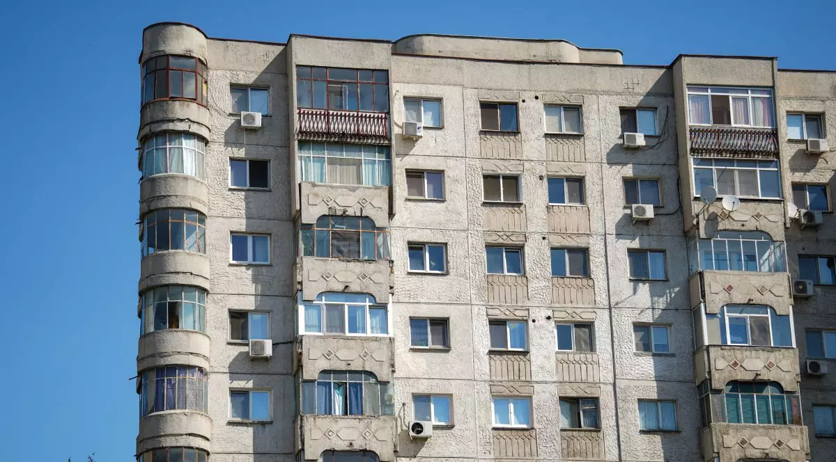 Un bloc vechi de apartamente, în București, cu fațada veche, iar pe fundal cerul albastru