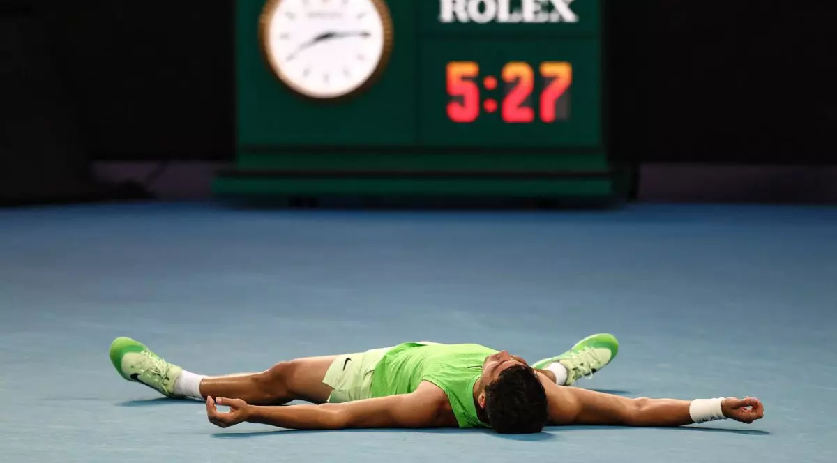 Carlos Alcaraz, îmbrăcat într-un maiou verde și purtând banderole albe marca nike în jurul încheieturilor, stând întins pe spate, cu mâinile și picioarele depărtate. în fundal se vede un cronometru marcat cu logo-ul Rolex, care arată „5.27”