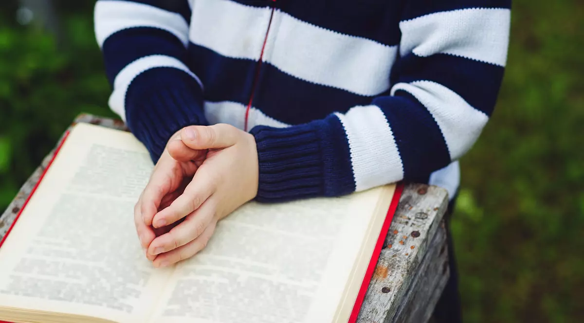 Copil care citeste din Bibilie și se roagă