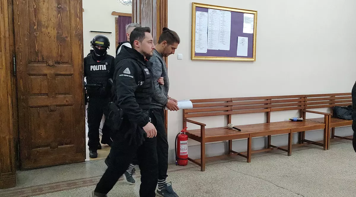 Un criminal este adus de polițiști la tribunal