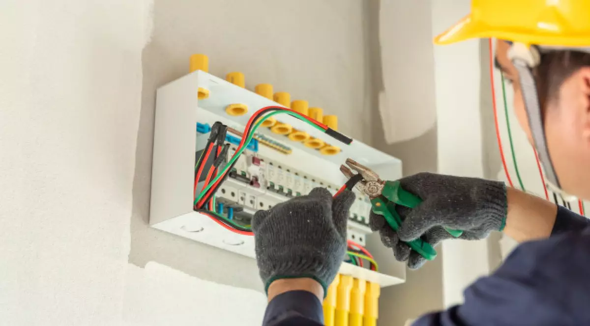 Un electrician instalează prize electrice noi într-o casă modernă, asigurându-se că toate conexiunile sunt sigure și eficiente.