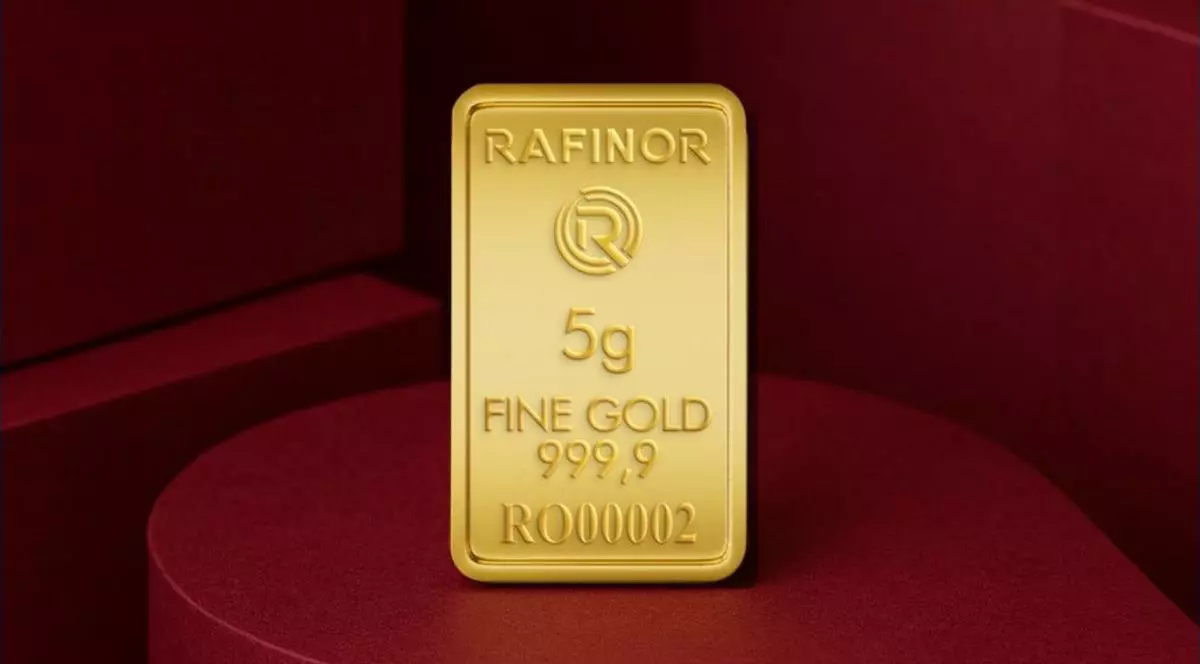 Un lingou din aur, de 5 grame, cu sigla firmei românești Rafinor, este pus în picioare pe o masă vișinie