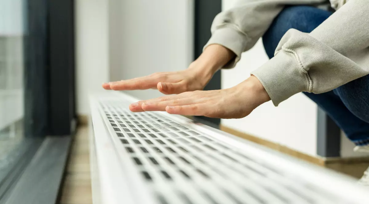 O femeie care ține mâinile deasupra unui calorifer.