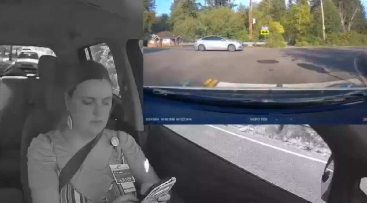 O femeie la volan, surprinsă de o cameră din mașină în timp ce tastează pe telefon.