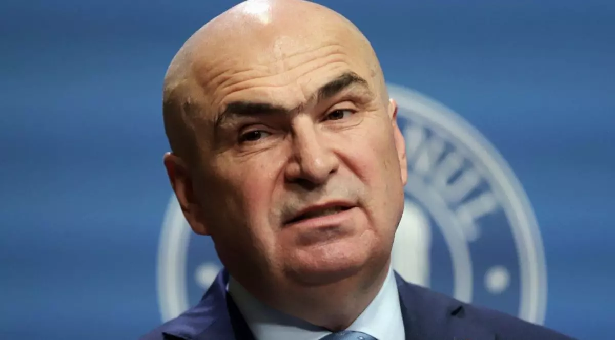 Premierul Ilie Bolojan, îmbrăcat la costum și cravată, se strâmbă ușor în timpul unei conferințe de presă, iar în spate are sigla Guvernului care este acoperită parțial de capul lui, București, ianuarie 2026