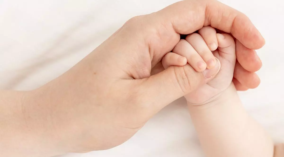 O femeie care ține mâna unui bebeluș.