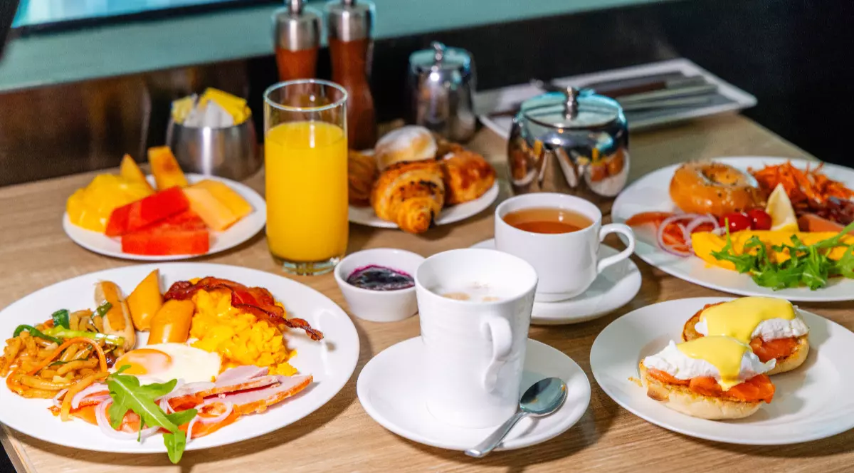 Felurile de mâncare pregătite pentru micul dejun, sunt așezat pe o farfurie ouă ochiuri, cafea în ceașcă, fructe și ouă benedict