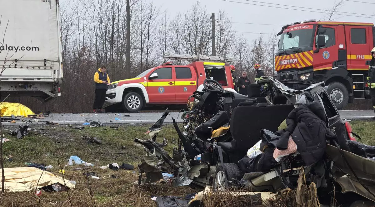 resturi de plastic și metal de culoare neagră așezate într-o grămadă uniformă pe marginea părții carosabile. în fundal se vede șoseaua, unde este parcată o autospecială de pompieri și o mașină de descarcerare