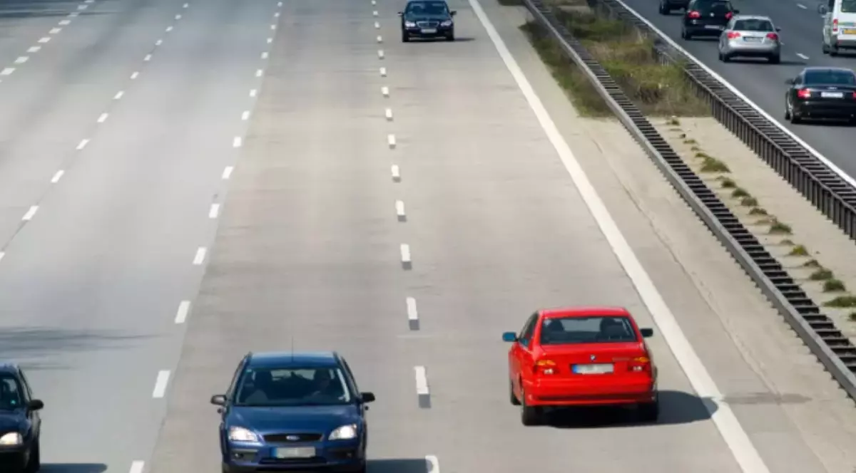 O mașină roșie care circulă pe contrasens, pe o autostradă.