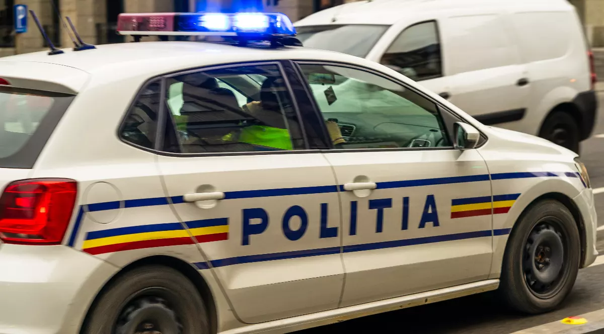 O mașina de Poliție cu doi polițiști în față și sirenele pornite, în timp ce se deplasează la o intervenție