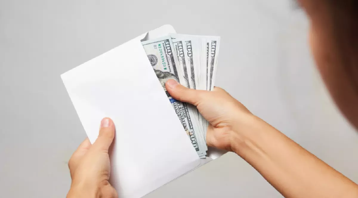 Mâna unei femei scoate bani dintr-un plic alb