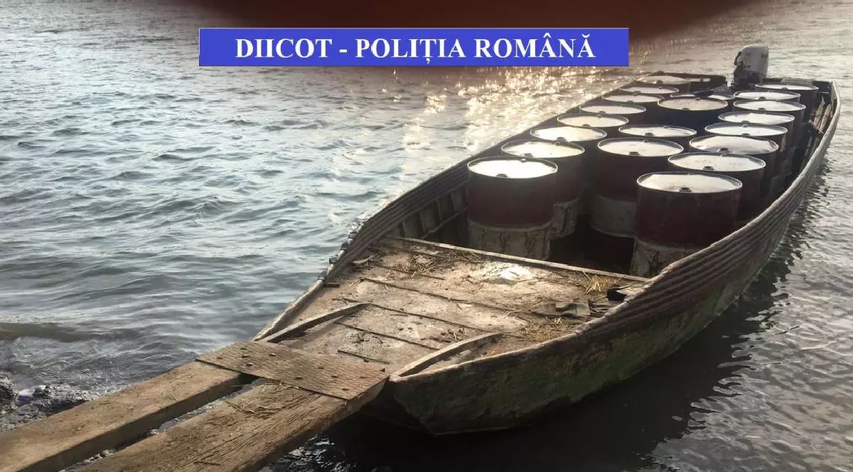 O barcă de lemn cu mai multe butoaie la bord, plutește pe un râu, cu textul în limba română „DIICOT - POLITIA ROMANA” suprapus în partea de sus.