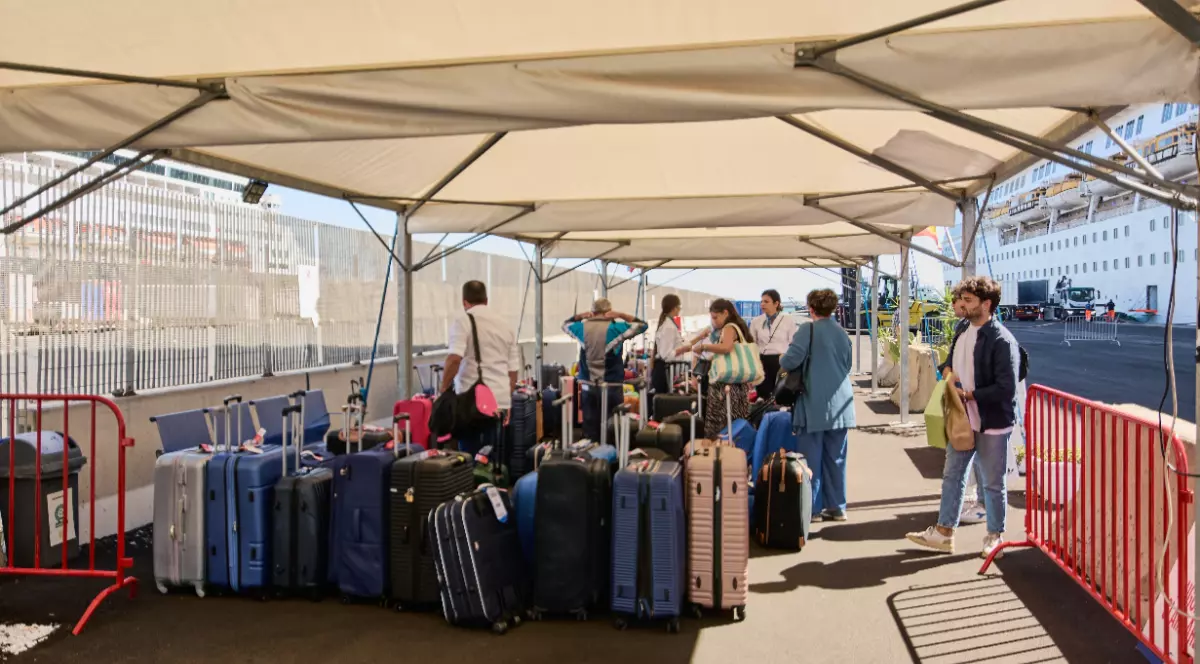 Un grup de turiști cu tot cu valize și bagaje, în timp ce așteaptă să se îmbarce la bordul navelor de croazieră