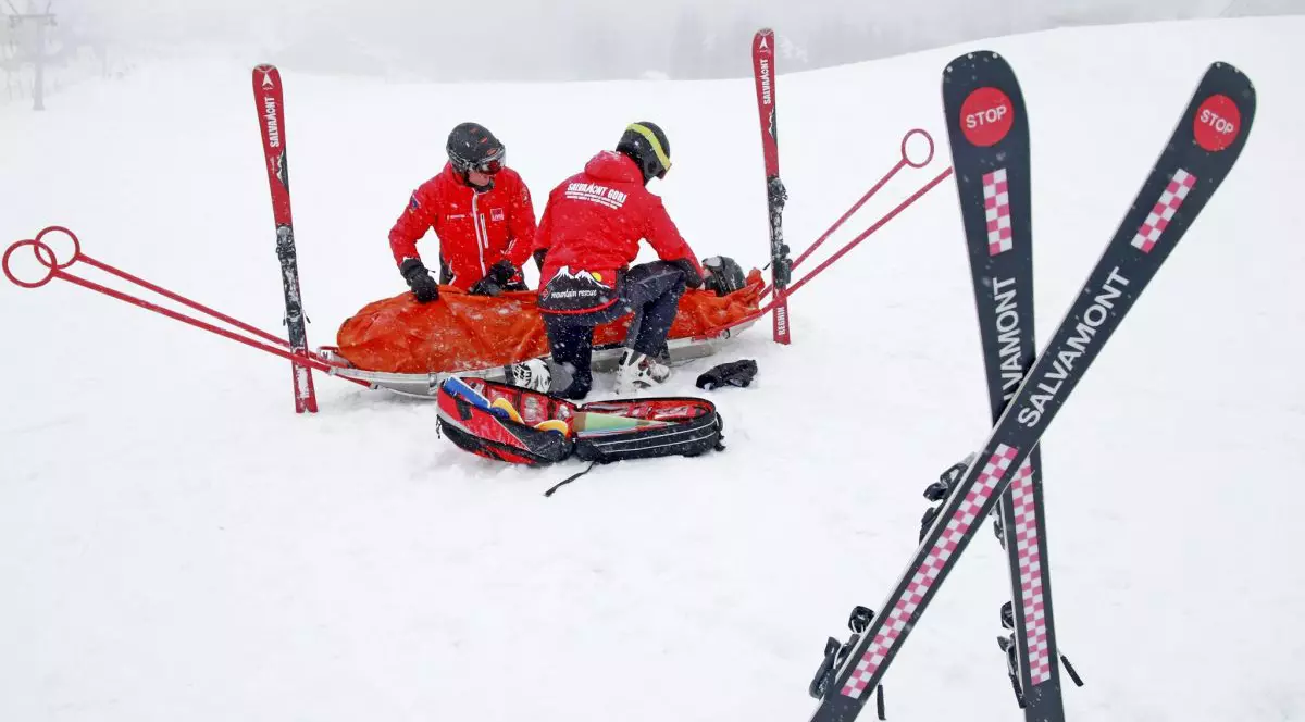 Doi salvamontiști pun pe o targă un bărbat care s-a accidentat pe munte