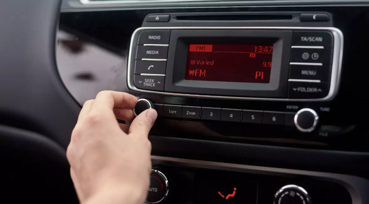 O femeie care pornește un aparat de radio FM într-o mașină mai veche