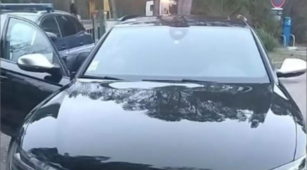 Un Audi negru parcat. Lângă acesta se află o mașină de jandarmerie.