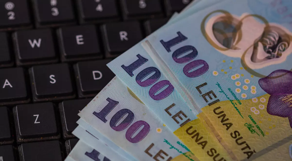 Mai multe bancnote de 100 lei pe o tastatură