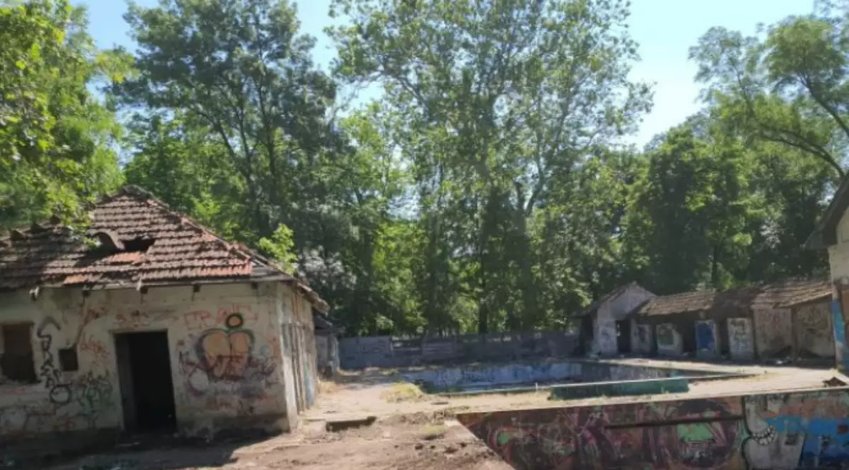 Ruinele abandonate ale bazei „Uszoda” din Timișoara. Sunt evidențiate clădiri deteriorate și bazine goale acoperite de graffiti colorat.