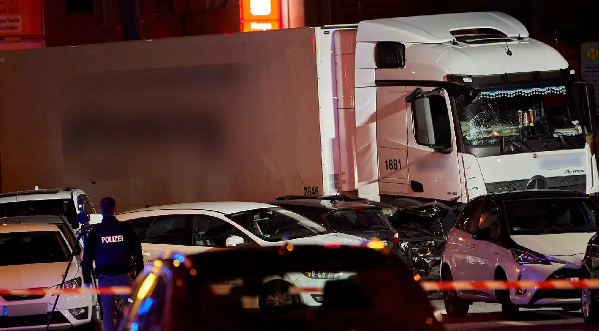 Fotografia arată un camion alb și mai multe mașini, noaptea, oprite pe o stradă, în urma unui accident. În imagine este surprins și un polițist cu spatele la aparatul foto.