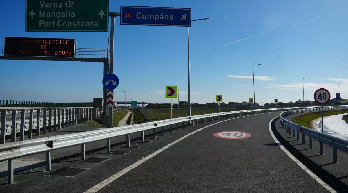 Imaginea surprinde o bretea de acces către Autostrada A4, cu indicatoare rutiere care arată direcțiile spre Cumpăna, Mangalia, Varna și Portul Constanța. Drumul este nou asfaltat, bine semnalizat, iar limita de viteză este de 40 km/h pe sectorul de ieșire.