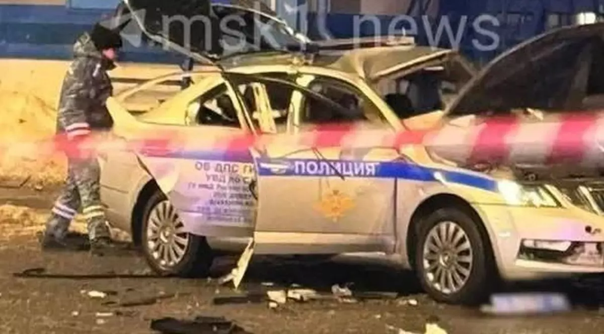 O mașină de poliție avariată, mai multe bucăți din ea sunt pe jos, un jandarm se uită la autoturism, după ce a avut loc o explozie și un bărbat a detonat un dispozitiv exploziv lângă mașina de patrulare a poliției, la Moscova, Rusia, în piața gării Saviolovski, 24 februarie 2026