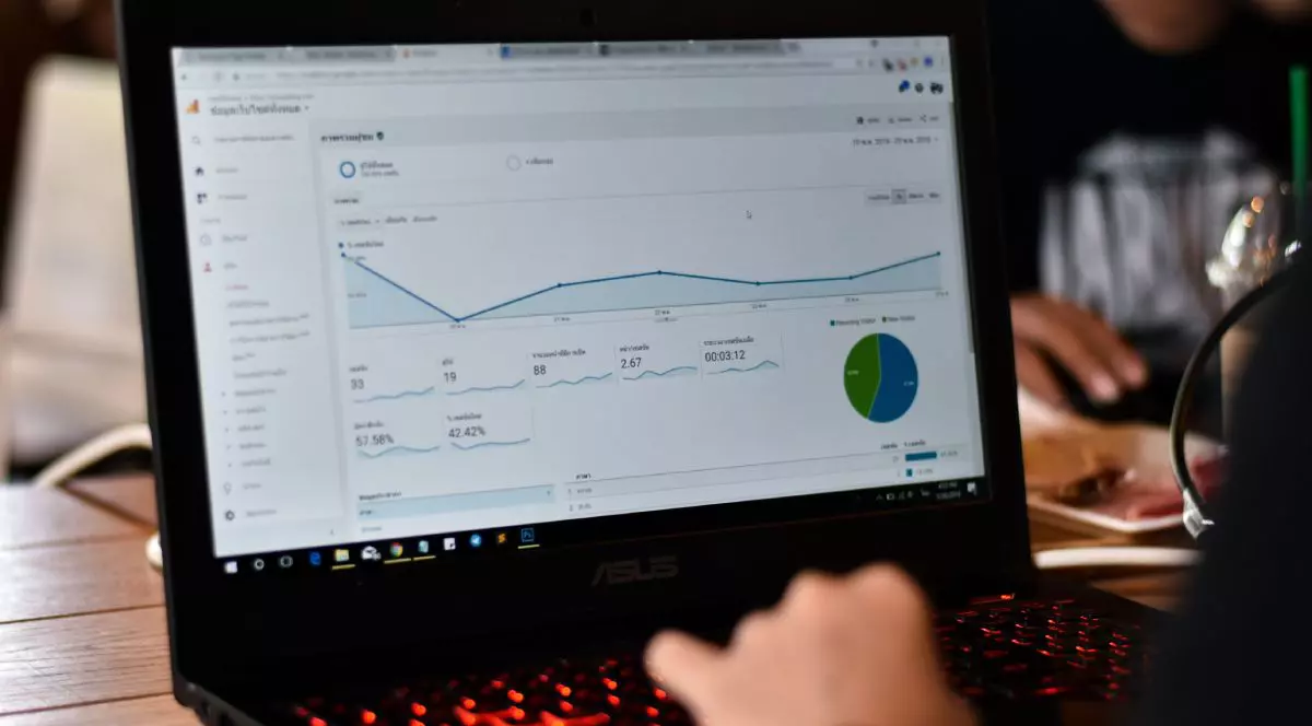Mâna unei persoane pe tastatura unui laptop ce are pe ecran aplicația Google Analytics