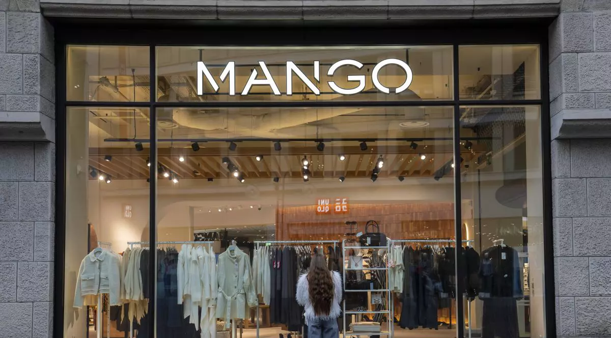 O femeie se uită de afară la produsele expuse de un magazin Mango din Koln, Germania