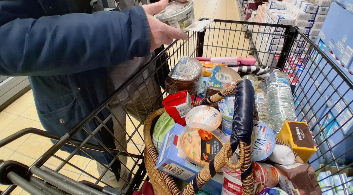 O femeie pune un produs în coșul plin de cumpărături într-un magazin din Germania,