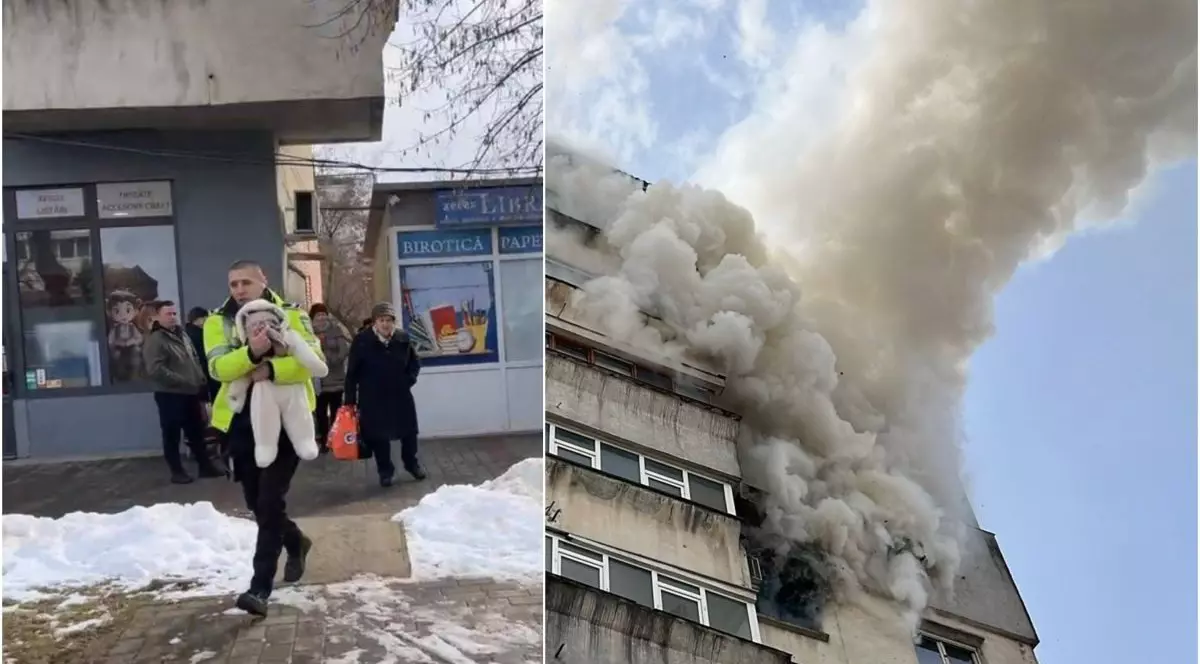 În stânga imaginii este un polițist care a salvat un bebeluș dintr-un incendiu și merge cu el în brațe, în spatele lui sunt niște oameni, iar în dreapta imaginii este un bloc, iar la un etaj se văd flăcări de la un incendiu, în Iași, 21 februarie 2026