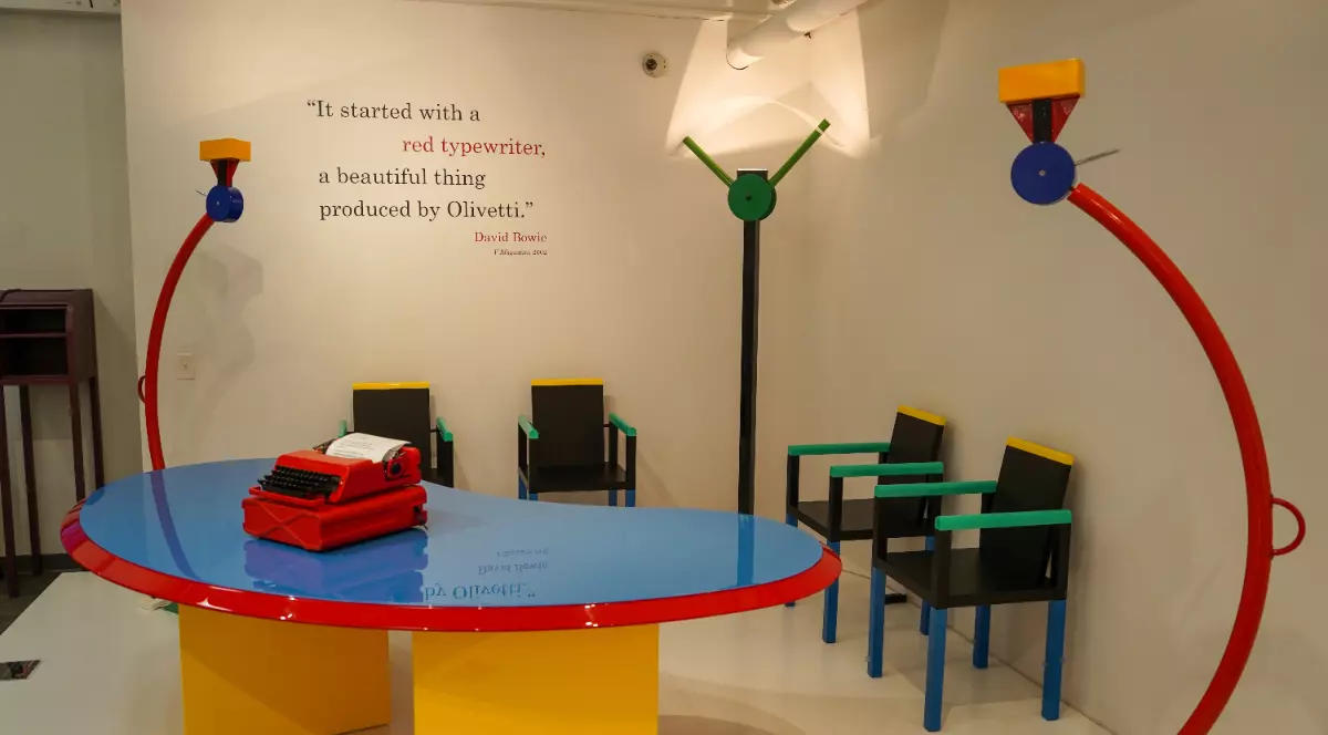 O cameră cu prețeti albi și o masă cu scaune colorate, în forme speciale