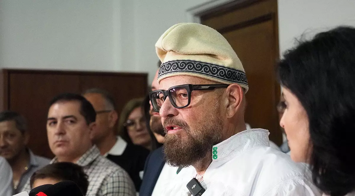 Un barbat imbt=racat in camasa alba si o caciula traditionala pe cap