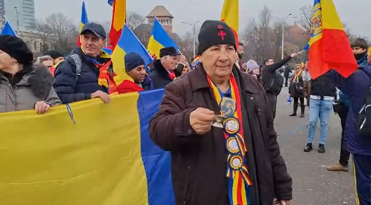 un bătrân este surprins tămâind mulțimea, în timp ce în jurul lui se aud scandările „Jandarmeria apără hoția!”.