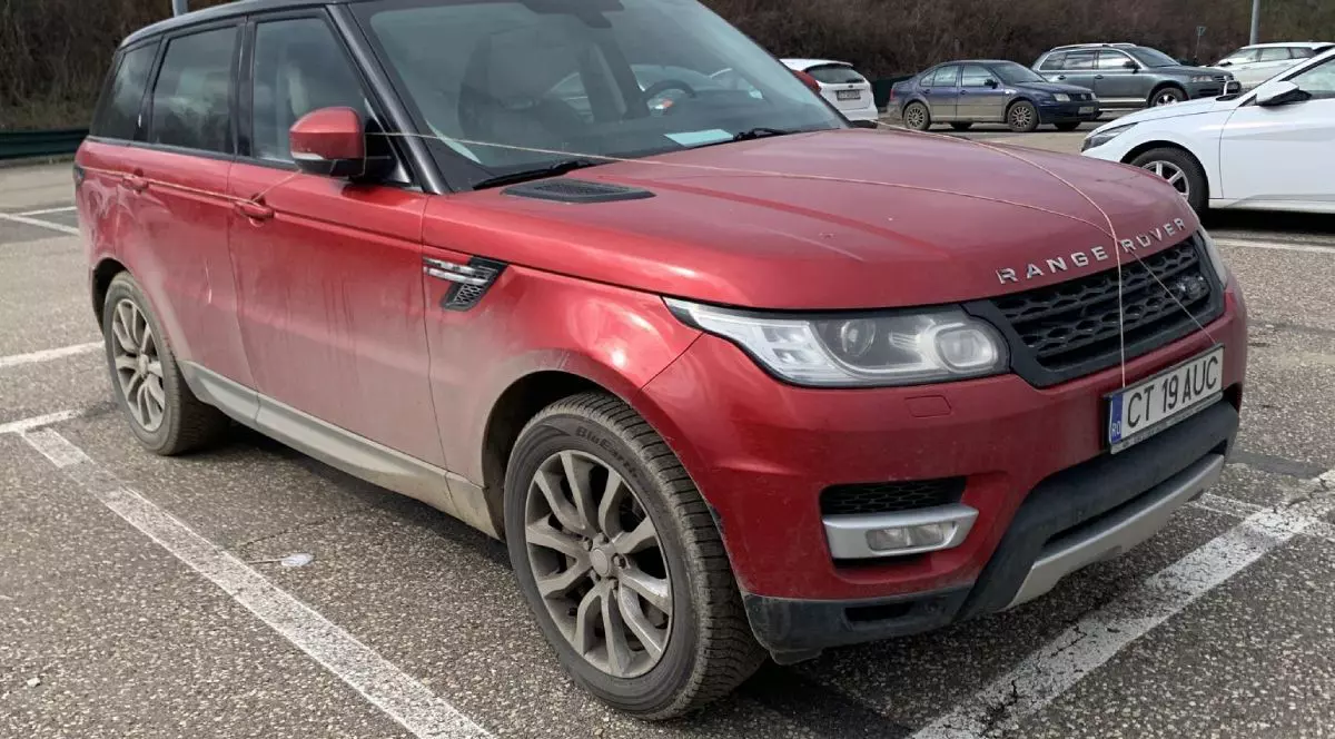 Range Rover Sport, din anul 2014, de culoare roșie, aflat într-o parcare, murdar pe caroserie