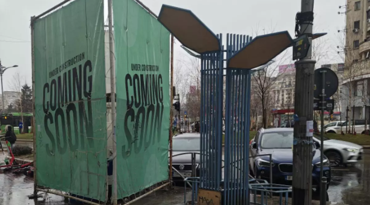 Un panou publicitar verde, marcat cu mesajul „Coming Soon”, pe un trotuar din București.