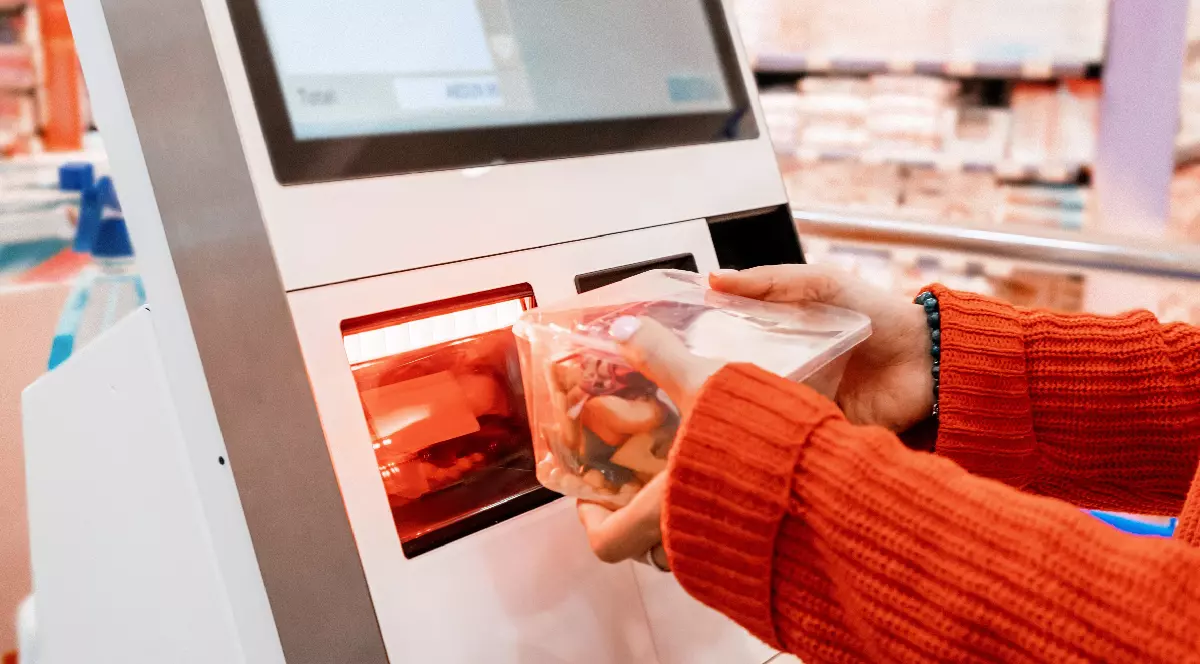 O femeie scanează un produs la o casă de marcat de tip self-service într-un supermarket