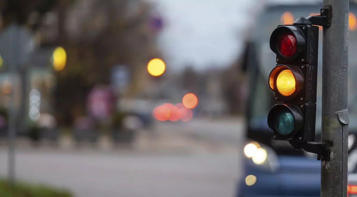 Un semafor pe un stâlp, culoarea galbenă e aprinsă