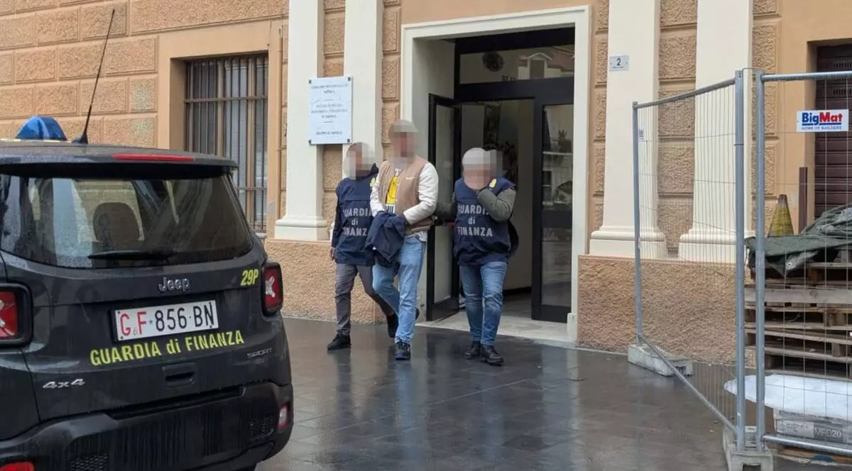 Un șofer român de TIR cu cătușe la mâini ascunse de o geacă (mijloc) este încadrat de doi polițiști, toți trei având fețele burate, Italia, 2 februarie 2026